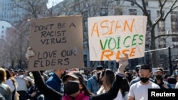 FILE - A woman holds up signs during a Rally Against Hate to end discrimination against Asian Americans and Pacific Islanders in New York City, March 21, 2021. 
