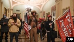 Pendukung Presiden AS Donald Trump, termasuk anggota kelompok konspirasi QAnon Jake Angeli alias Yellowstone Wolf (tengah), memasuki Gedung Capitol pada 6 Januari 2021, di Washington, DC. (Foto: AFP)