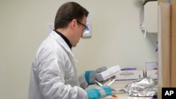 FILE - A pharmacist in Seattle opens a package taken from a freezer that contains a potential vaccine for COVID-19, on the first day of a first-stage safety study clinical trial of the vaccine, March 16, 2020.