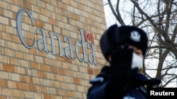 A police officer gestures at the photographer outside the embassy of Canada in Beijing, China, Dec. 12, 2018. 