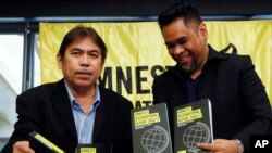 Amnesty International, Philippines' Jose Noel Olano, left, and Wilnor Papa, hold copies of the 2016/17 Amnesty International report which they released at a news conference, Feb. 22, 2017, in suburban Quezon city northeast of Manila, Philippines. 