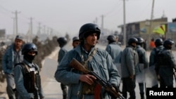 FILE - Afghan policemen keep watch at the site of clashes with protesters in Kabul, Jan. 31, 2015. 