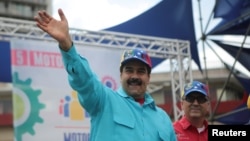 Venezuela's President Nicolas Maduro, left, and Venezuela's Economy and Productivity Vice President Miguel Perez Abad greet supporters during a rally in Caracas, Venezuela, May 14, 2016. 