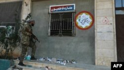 Seorang pemberontak memeriksa pangkalan milik brigade Fatemiyoun yang didukung Iran di kota Khan Sheikhun, di Provinsi Idlib, Suriah barat laut pada 1 Desember 2024. (Foto: AFP)