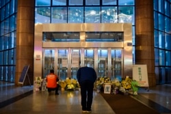 FILE - A man bowing in front of flowers and a photo of the late ophthalmologist Li Wenliang outside the Houhu Branch of Wuhan Central Hospital in Wuhan in China's central Hubei province, Feb. 7, 2020.