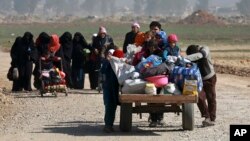 FILE - Iraqi civilians walk toward Iraqi security forces after fleeing their homes because of fighting between government forces and Islamic State militants, on the western side of Mosul, Iraq, March 9, 2017.
