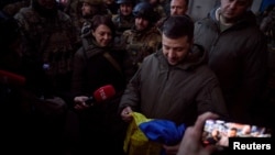Ukraine's President Volodymyr Zelenskyy holds a national flag as he visits a position of Ukrainian service members in the frontline town of Bakhmut, amid Russia's attack on Ukraine, in Donetsk region, Ukraine Dec. 20, 2022.