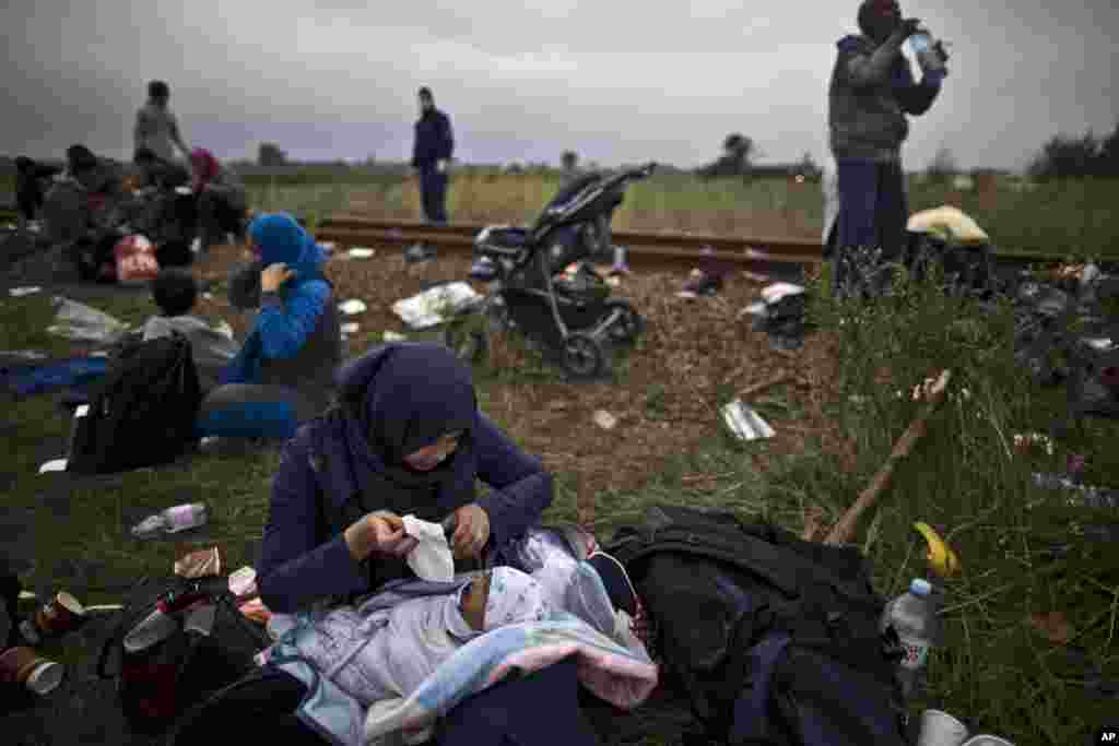 Iraqi refugee Umm Fadil, tends to her crying son, while resting by a railway track after they crossed the Serbian-Hungarian border near Roszke, southern Hungary. EU officials and human rights groups say they've been disappointed by the animosity toward asylum-seekers in countries from which hundreds of thousands of people fled communist dictatorships just decades ago.