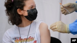 A girl gets a Pfizer-BioNTech COVID-19 vaccine in Bucharest, Romania, June 2, 2021. Britain's Medicines and Healthcare products Regulatory Agency on Friday approved the vaccine for 12- to 15-year-olds. 