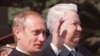 FILE - Russian President Vladimir Putin, left, waves as he stands with former President Boris Yeltsin during a parade on Red Square, in Moscow, May 9, 2000. 