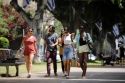 Pedestrians walk on a boulevard as Israel rescinds the mandatory wearing of face masks outdoors, in Tel Aviv, Apr. 18, 2021.