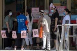 Residents line up to enter a supermarket near a barrier with the words "Do Not Cross," in Beijing, China, June 15, 2020.