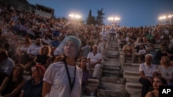 An usherette wearing a face shield stands in front of the audience at the Odeon of Herodes Atticus in Athens, Greece, after the site was reopened for performances on July 15, 2020.