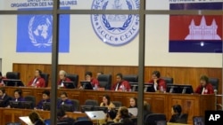 FILE - Extraordinary Chambers in the Courts of Cambodia, court officers of the U.N.-backed war crimes tribunal are seen through windows during a hearing of former Khmer Rouge top leaders in Phnom Penh. 
