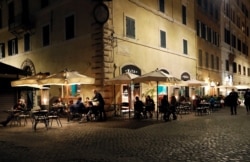 People sit outside a bar near Campo de' Fiori before a curfew imposed by the region of Lazio from midnight to 5 a.m to curb the coronavirus disease infections in Rome, Italy, Oct. 23, 2020.