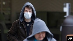 A man wearing a mask walks away from the entrance of the Life Care Center in Kirkland, Wash., near Seattle, March 3, 2020. 