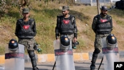 Paramilitary soldiers stand guard with riot gears at a road barricaded with shipping containers ahead of a planned rally by supporters of imprisoned former Prime Minister Imran Khan's Pakistan Tehreek-e-Insaf party, in Islamabad, Nov. 24, 2024.