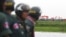 FILE - Cambodian police officers stand guard as Vietnamese people wave their national flags at the Cambodia-Vietnam border in Svay Rieng province, July 19, 2015. 