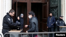 A security officer checks the belongings of a tourist entering Milan's Duomo cathedral, as it reopens to the public for the first time since the coronavirus outbreak in northern Italy, in Milan, Italy, March 2, 2020.