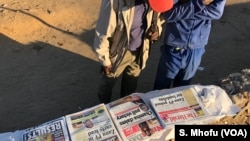 Zimbabwean men reading newspaper headlines, Wednesday morning two days after the country held its first general election without founding leader Robert Mugabe on the ballot. 
