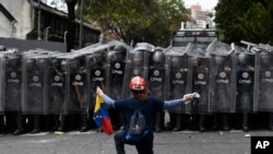 FILE - A man kneels in front of police blocking a march called by opposition leader Juan Guaido, in Caracas, Venezuela, March 10, 2020. 