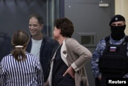 FILE - Wall Street Journal reporter Evan Gershkovich, who is in custody on espionage charges, speaks with his lawyers while standing behind a glass wall of an enclosure for defendants as he attends a court hearing in Moscow, Russia, April 23, 2024.