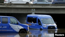 A driver moves his airport shuttles van through flood waters following an El Nino-strengthened storm in San Diego, California, Jan. 6, 2016.