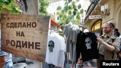 FILE - T-shirts, displaying images of Russia's President Vladimir Putin, are on sale at GUM department store in central Moscow, June 11, 2014. The sign reads "Made in Fatherland." 