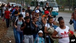FILE - In this April 10, 2019 file photo, migrants walk at dawn as part of a new caravan of several hundred people sets off in hopes of reaching the distant United States, in San Pedro Sula, Honduras. (AP Photo/Delmer Martinez, File)
