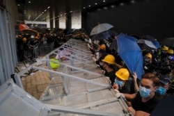 FILE - Protesters are seen as they forcefully enter the Legislative Council in Hong Kong, July 1, 2019.