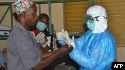 Health workers take off their protective suits as they finish their shifts at the Pita hospital, Guinea, Aug. 25, 2014. 