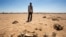 A man stands near the carcass of a domestic animal that died due to severe drought in Baligubadle village near Hargeisa, the capital city of Somaliland, in this handout photo provided by The International Federation of Red Cross and Red Crescent Societies