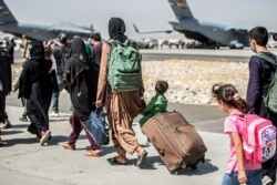 Families walk towards their flight during evacuations at Hamid Karzai International Airport, in Kabul, Afghanistan, Aug. 24, 2021, in this photo provided by the U.S. Marine Corps.