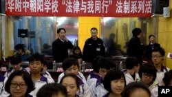 Government workers stand under a banner that reads "Tsinghua-affiliated Chaoyang School, The Law and me together, legal series of talks" as they observe a student meeting on legal matters on Constitution Day in Beijing, Dec. 4, 2014.