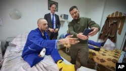 Ukrainian President Volodymyr Zelenskyy, right, and Netherland's caretaker Prime Minister Mark Rutte, center, pose for a photo with a wounded Ukrainian soldier in a hospital in Odesa, Ukraine, on Oct. 13, 2023. (Ukrainian Presidential Press Office via AP)