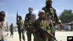 FILE - A young boy leads militant Islamist al-Shabab fighters as they conduct military exercises in northern Mogadishu's Suqaholaha neighborhood, Somalia, Jan. 1, 2010.