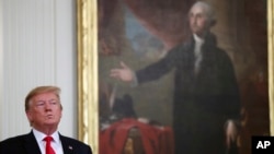FILE - President Donald Trump stands near a portrait of George Washington in the East Room of the White House, April 18, 2019, in Washington.