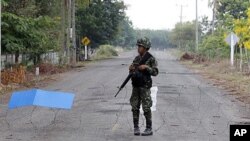 A Thai soldier mans a razor-wire roadblock close to the Thai-Cambodia border, shortly before cross-border fighting resumed for a third day, April 24, 2011