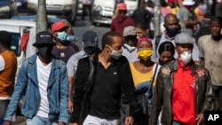 People wearing face masks to protect against coronavirus, walk on the street in downtown Johannesburg, South Africa, May 11, 2020. 