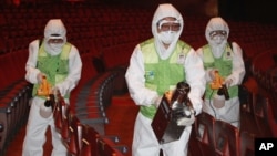 Workers wearing protective gears, spray antiseptic solution as a precaution against the spread of MERS, Middle East Respiratory Syndrome, virus at the Sejong Culture Center in Seoul, South Korea, Tuesday, June 16, 2015. 
