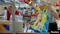 A shopper puts groceries he bought in his own bag after stores in China stopped giving free plastic bags at a supermarket in Beijing, June 1, 2008. 