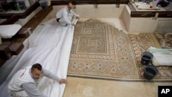 In this Dec. 6, 2018 photo, restoration experts work on a mosaic inside the Church of the Nativity, built atop the site where Christians believe Jesus Christ was born, in the West Bank City of Bethlehem.