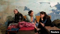 FILE - Local residents sit inside a bomb shelter where they are seeking refuge during what they say is shelling in Donetsk.