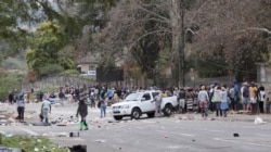 People stand on the roadside after being evicted following protests that have widened into looting, in Durban, South Africa, July 13, 2021, in this screen grab taken from a video. (Courtesy Kierran Allen/via Reuters)
