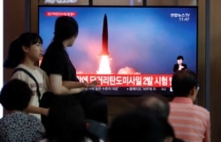FILE - People watch a screen that shows a file photo of a North Korean missile for a news report on North Korea firing short-range ballistic missiles, in Seoul, South Korea, July 31, 2019.