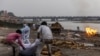 People place the body of a man who died from COVID-19 on a pyre before his cremation on the banks of the river Ganges at Garhmukteshwar in the northern state of Uttar Pradesh, India, on May 6, 2021.