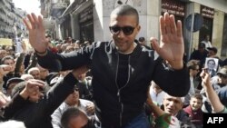 FILE - Algerian journalist Khaled Drareni is carried by protesters on their shoulders after he was briefly detained by security forces in Algiers, March 6, 2020.