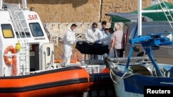 Emergency services carry a body at the dock of Le Castella after a migrant boat caught fire during rescue operations off the coast of Crotone, with some people still missing according to Italian media, Italy, Aug. 30, 2020. 