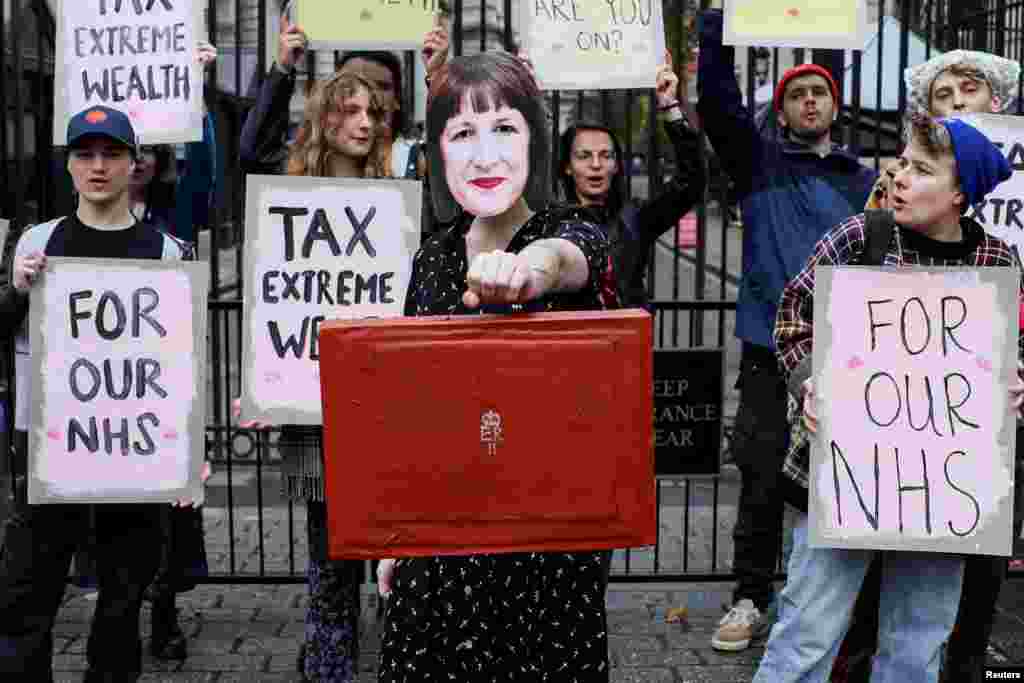 A demonstrator holds a mock red budget box while wearing a mask representing Britain's Chancellor of the Exchequer Rachel Reeves, during a protest outside Downing Street in London, Britain.