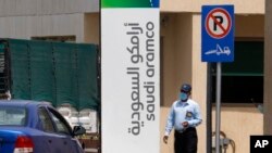 FILE - A security person wears a mask as he checks vehicles entering a compound for Saudi Aramco in Jiddah, Saudi Arabia, March 9, 2020. 
